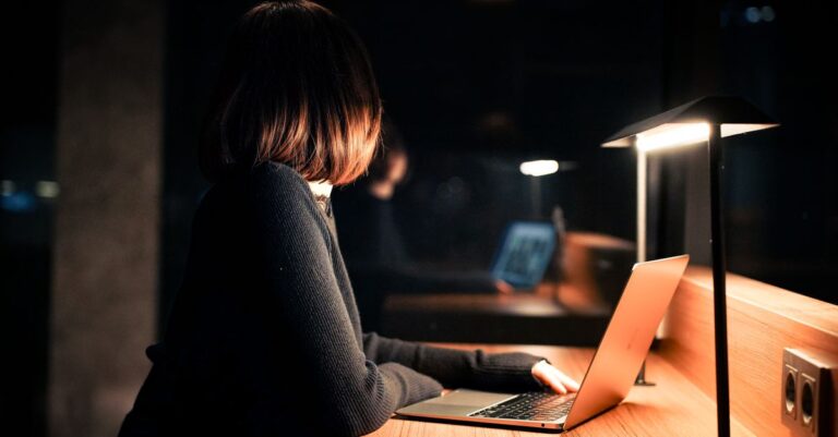 Mujer trabajando de noche en una laptop protegida con un antivirus