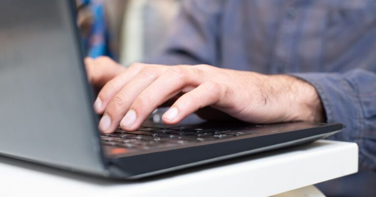 Persona escribiendo su password en el teclado de la laptop para recuperar su cuenta