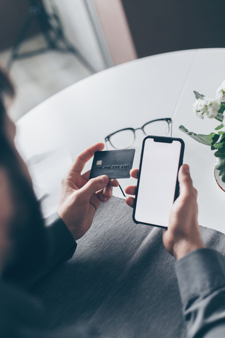 Persona usando una tarjeta y un teléfono para realizar un pago en línea